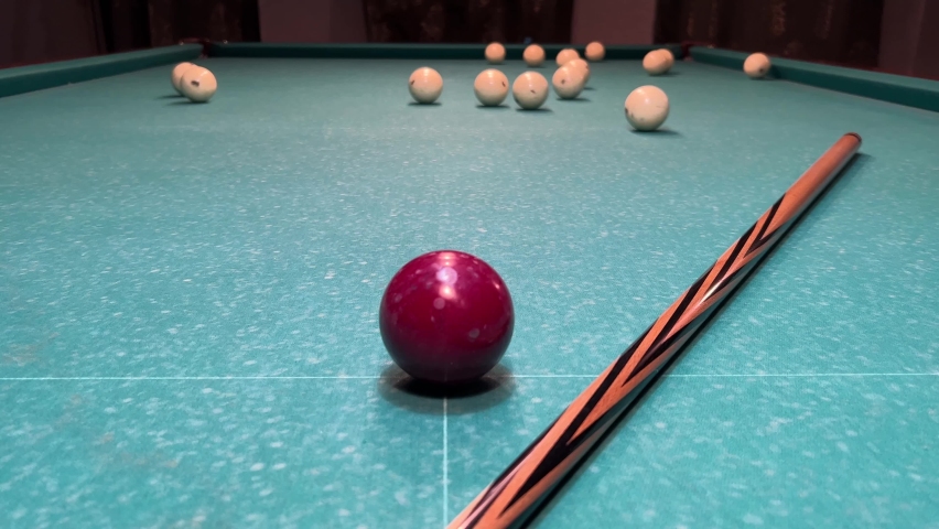 The green canvas of the Russian billiards on which the cue and the red ball lie