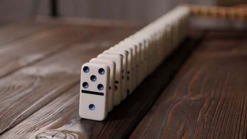 Hand of pushing dominoes on wooden background. Planning risk and strategy concept for begin work process. Domino Effect Concept.