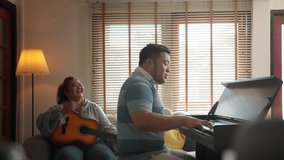 Romantic happy fat asian couple happy to play music with piano and classical guitar at home on weekend. Young male and female freelance musician enjoy rehearsing dance and singing. new life - Powered by Shutterstock - Get 15% off with code: PIKWIZARD15