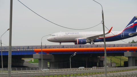 MOSCOW, RUSSIAN FEDERATION - JULY 28, 2021: Airbus A320 of Aeroflot taxiing over the highway at Sheremetyevo airport. Car traffic in the foreground. Aeroflot Russian Airlines public-private airline