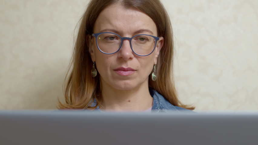 A young woman in glasses works on a laptop. | Shutterstock HD Video #1090481153
