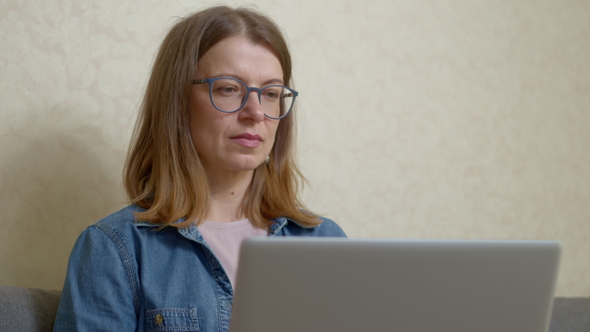 A young woman in glasses works on a laptop. | Shutterstock HD Video #1090481155