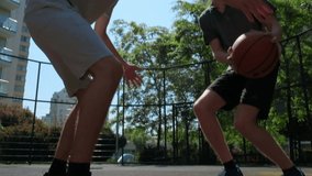 People playing street basketball during a warm summer day. Two teens playing a basketball match on an outdoors court during a sunny summer day. Attack and defence, missed shot.
