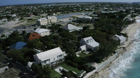 Aerial camera whirls above colonial houses in Cockburn Town, drone view of Sargasso coastline in Grand Turk, Turks and Caicos
