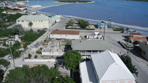 Aerial camera whirls above roads and houses in Cockburn Town, Grand Turk, Turks and Caicos, drone video of tropical island coastal area
