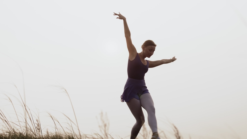 Confident ballerina dances in pointe shoes, outdoor. Caucasian ballerina dances sky in sports dress. Concept of dance creativity and choreography | Shutterstock HD Video #1090484023