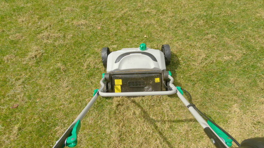 POINT OF VIEW: Gardener using grass aerator while taking care of backyard lawn. First person view of spring home garden work for green lawn growth enhancement. Practical machinery for landscaping. | Shutterstock HD Video #1090484199