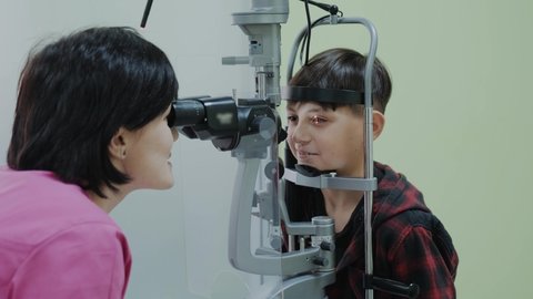 Doctor Ophthalmologist checking boy with eyesight examination at clinic with a slit lamp