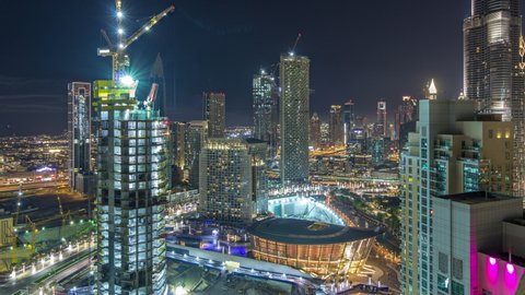 Dubai downtown night timelapse, illuminated luxury modern buildings, futuristic cityscape of United Arab Emirates. Aerial top view with construction site from skyscraper