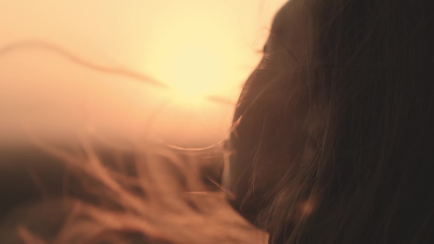 girl prays looking at sunset, long hair is flying away in glare of sunlight rays in strong wind, looking at dawn, lonely hike of brave girl, looking into sky with her eyes, believing good. Royalty-Free Stock Footage #1090488401