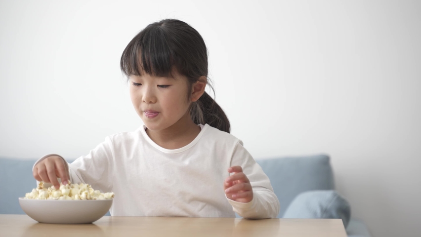 asian girl eating popcorn in the living room