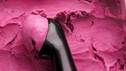 Strawberry ice cream scooping out of container by spoon. Surface of pink ice cream. Delicious dessert. Close-up in 4K, UHD
