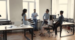 Interested diverse coworkers listen to young male project executive on work seminar ask questions discuss project strategy. Happy multicultural workforce group teamworking at modern open space office - Powered by Shutterstock - Get 15% off with code: PIKWIZARD15