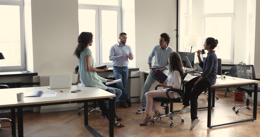 Interested diverse coworkers listen to young male project executive on work seminar ask questions discuss project strategy. Happy multicultural workforce group teamworking at modern open space office Royalty-Free Stock Footage #1090496101