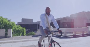Animation of yellow dots over african american businessman riding on bike in city. healthy active lifestyle, living in city concept digitally generated video.