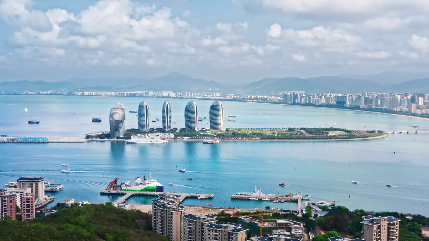 Aerial footage of beautiful city skyline and buildings with sea natural scenery in Hainan Island, China. Drone fly over the city of Sanya. Famous travel destination in China.