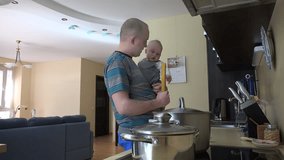 Father man with baby in hands and mother woman put spaghetti in steamy pot. Happy family cook in kitchen. Static shot. 4K UHD video clip.