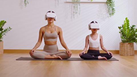 Relax mom and kid doing yoga at home together,VR goggles in modern lifestyle.Practicing yoga workout in virtual reality glasses.Yoga training for health with future digital tech exercise Metaverse