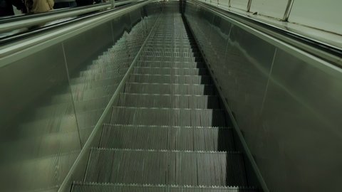 FPV First person view of moving empty escalator stairs, escalator moves steps down. Slow motion