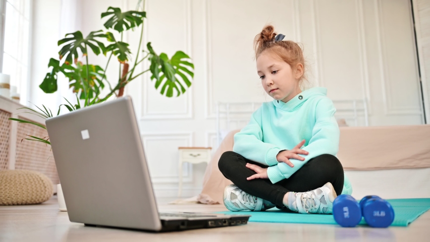 Girl sitting near a laptop with boredom looking at the screen next to sports equipment. Distance learning physical education. Children and technology 21 century Royalty-Free Stock Footage #1090505987