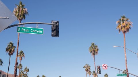 Palm trees and sky, Palm Springs street, city near Los Angeles, semaphore traffic lights on crossroad. California desert valleys summer road trip on car, travel USA. Mountain. Palm Canyon road sign