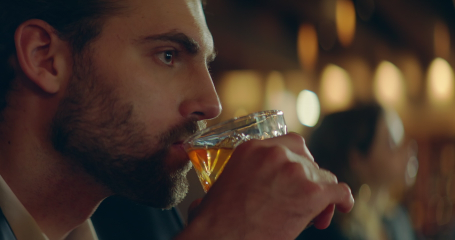 CU Portrait of handsome 30s adult Caucasian male enjoying a drink at the bar or restaurant in the evening. Shot with 2x anamorphic lens