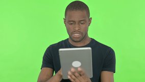 Video Call on Tablet by Young African Man on Green Background 
