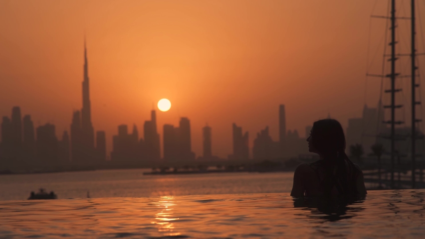 Dubai lifestyle video of travel woman in swimwear enjoying the Dubai skyline view at sunset in an infinity pool. Lifestyle and vacation concept in Dubai UAE  Royalty-Free Stock Footage #1090512559