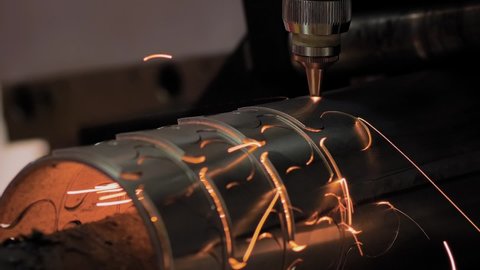 Automatic cnc laser cutting machine working with cylindrical metal workpiece with many sparks at factory, plant - close up, slow motion. Metalworking, industrial, manufacturing and equipment concept
