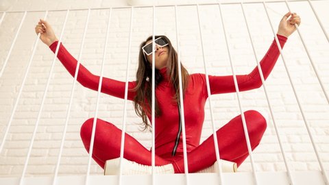 A beautiful female dancing in a loft apartment space wearing a fantastic red catsuit