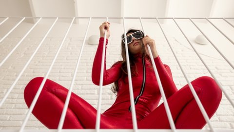 A beautiful female dancing in a loft apartment space wearing a fantastic red catsuit