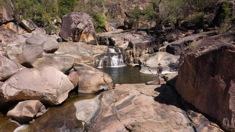 Man with Australian outback hat walks to waterfall, tourism hiking concept, Jourama Falls, Queensland