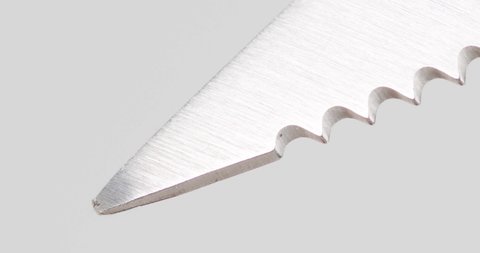 Sharp stainless steel knife tip on white background.