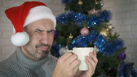 Lonely man with cup at Christmas. A pensive lonely man enjoy a hot tea by the Christmas tree in the room.