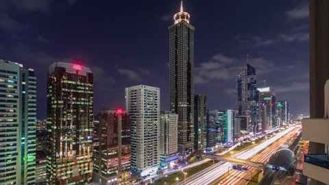 Downtown Dubai towers day to night transition timelapse. Aerial view of Sheikh Zayed road with skyscrapers after sunset. Traffic on the road and metro line. Beautiful cloudy sky