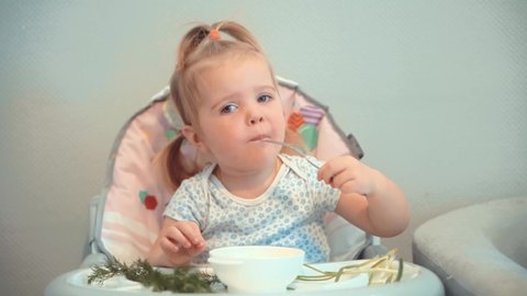 Funny Cute Little Children Sitting In Chair Kindergarten Eating Supplementary Healthy Food For Toddlers. Adorable Happy Infant Baby Eating. Cute Child Little Girl Eating Healthy Food In Kindergarten. 
