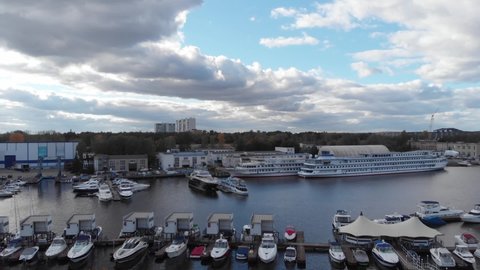 The camera flies over the yacht club on a summer day. The camera shoots up and a port with boats and yachts appears from behind the trees. High quality FullHD footage