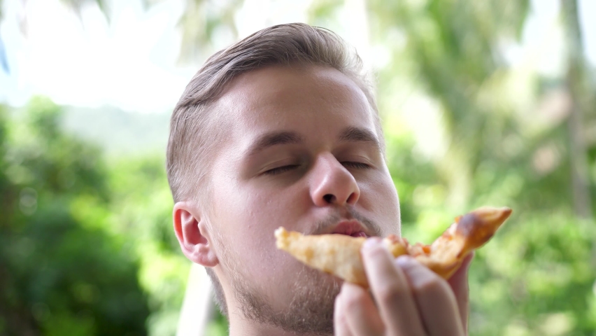 Caucasian man eating pizza. Hungry man taking a bite from pizza. Close up. | Shutterstock HD Video #1090525221