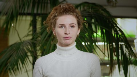 Close-up of a young woman with red curly hair, letting her hair down from a ponytail. Portrait of a girl