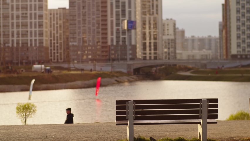 A couple in love walks in the park and sits on a bench. They are holding hands. The girl moves closer to the man. In the background are apartment buildings and a highway. Near a pond Royalty-Free Stock Footage #1090530929