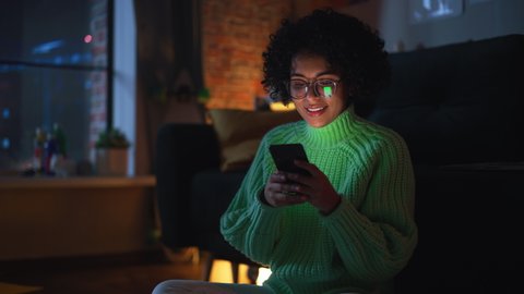 Latin Concentrated Woman Typing Message at her Smartphone During the Evening at Home. Internet Addicted Female Using Mobile Phone App for Online Shopping, Social Media, Internet Browsing