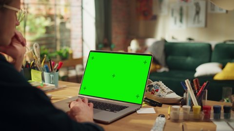 Concentrated Male Art Director Working From Home at Laptop with Green Screen. Man Using Touchpad with Serious Face while Thinking About New Project. Freelance and Millennial People Concept