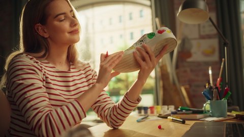 Zoom On of Female Designer Drawing on Shoes and Examining Result of Her Work with Satisfied Smile. Woman is Customising Shoes by Her Own Design. Art and Small Business Concept. Moving Shot