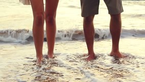 Close Up Shot of Couple's Legs in the Water on the Beach at Sunset.