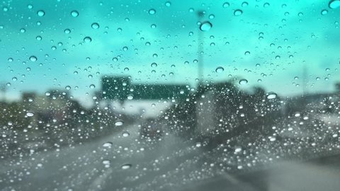 Defocused,Raindrops falling on car windshield,drive car on the road in city at heavy rain storm,colorful bokeh with street light,selective focus.