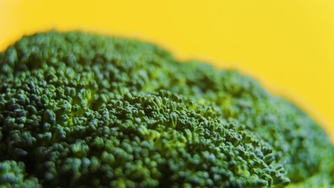 Close up Green fresh broccoli vegetables rotating on yellow isolated background. macro footage of Fresh raw broccoli rotating