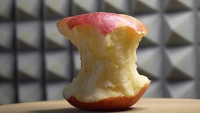 One red apple core on a rotating wooden surface, 4k close-up video. Apple core, side view.