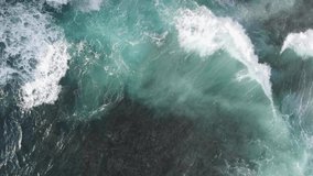 Shooting the ocean from a height with a drone. Top view of the large turquoise waves of the Indian Ocean. White foam from the waves and clear water with a rocky bottom. Video from the trip.