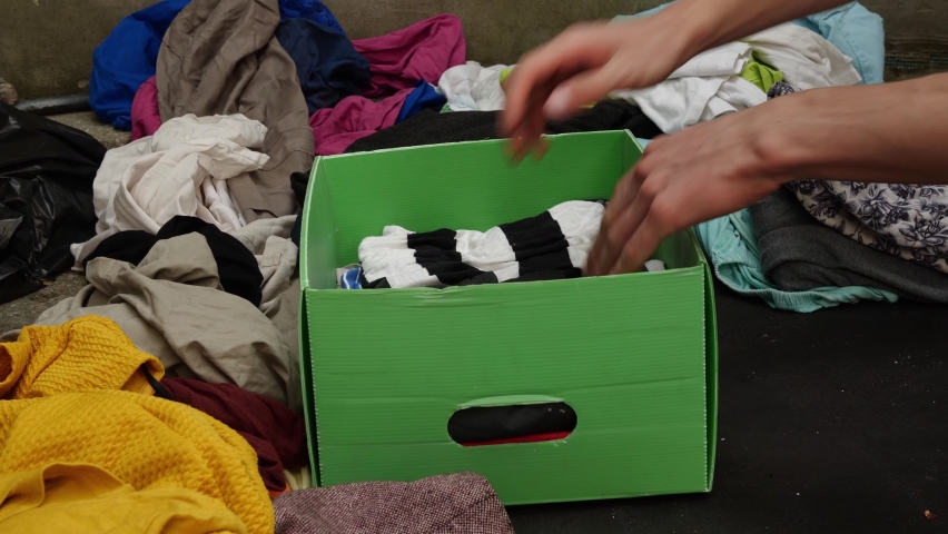 A person puts used clothes in a donation box for reuse