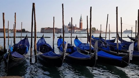 Gandolas sway on the waves in the canal of Venice. Moored tourist gondolas in Venice canal. Venice, Italy